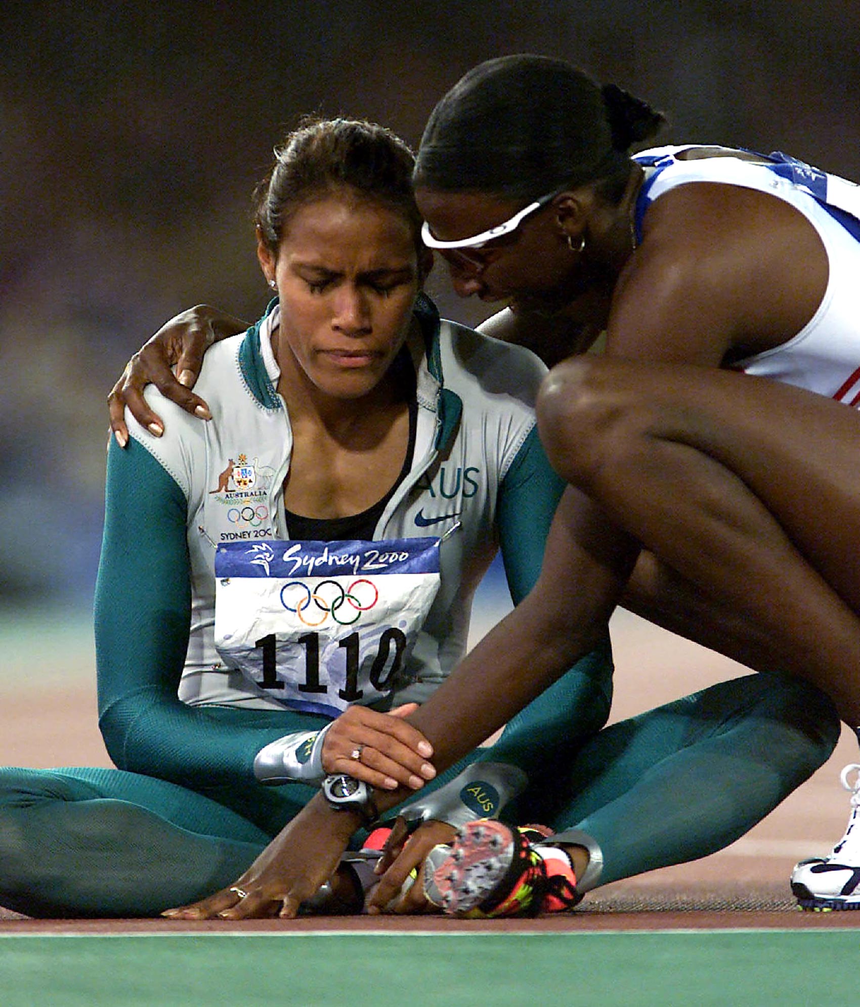   SEPTEMBER 25, 2000 : Athlete Cathy Freeman of Australia sits on track as she is congratulated by Donna Fraser of Great Britain after winning final of Women