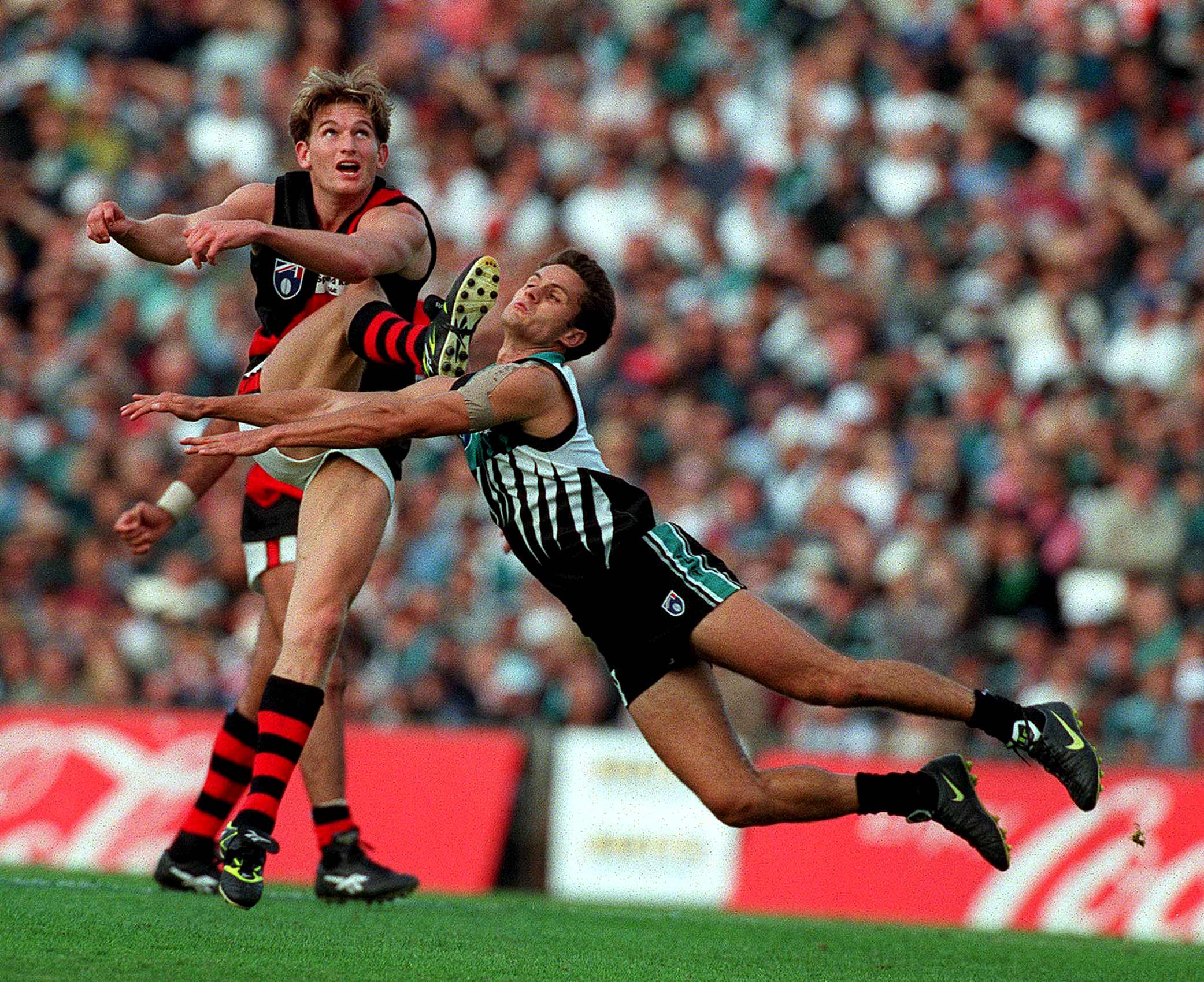   Port Adelaide v Essendon. Gavin Wanganeen dives in an attempt to smother former teammate James Hird.  